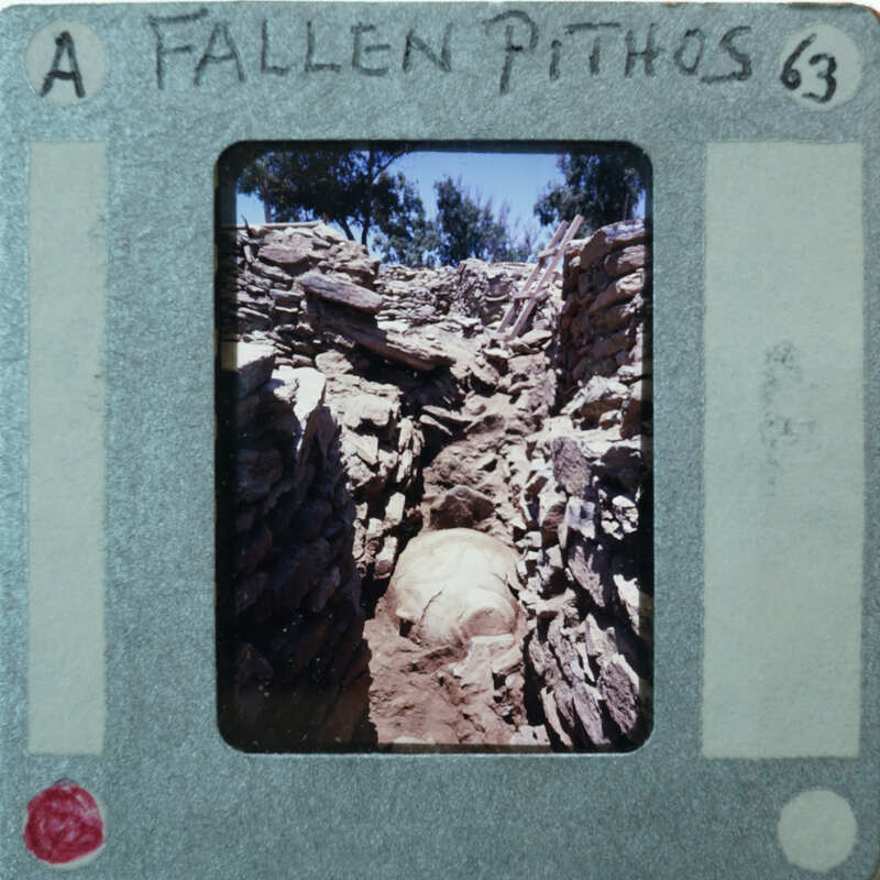 A photograph of a fallen pithos, which is an ancient Greek storage jar, with handwritten notes on the film strip.