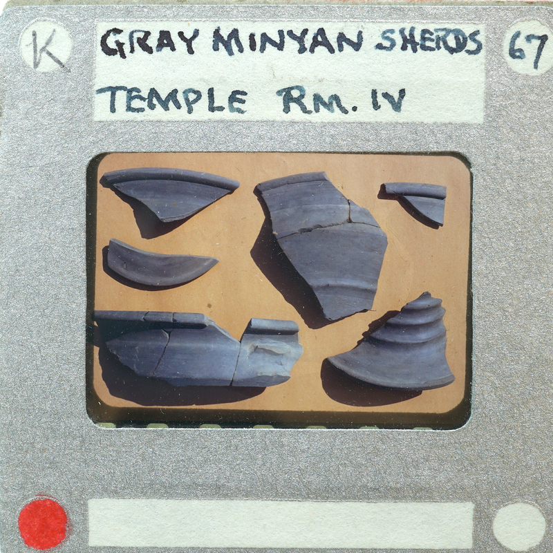 Image of a label with fragments of pottery and handwritten notes, possibly from an archaeological site or museum exhibit.