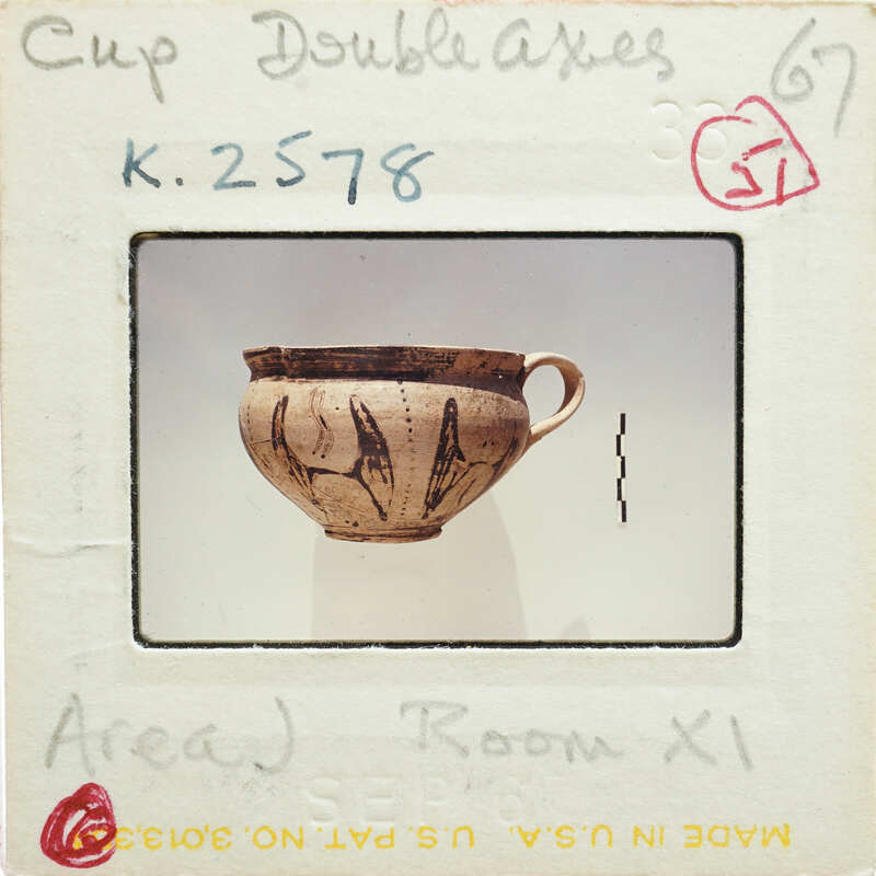A photograph of a ceramic cup with markings, displayed on a card labeled "CUP DOUBLE AXES" with handwritten notes and stamps.