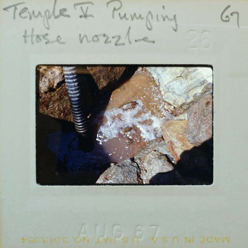 Hose for pumping water in a flooded floor surface, surrounded by stones.