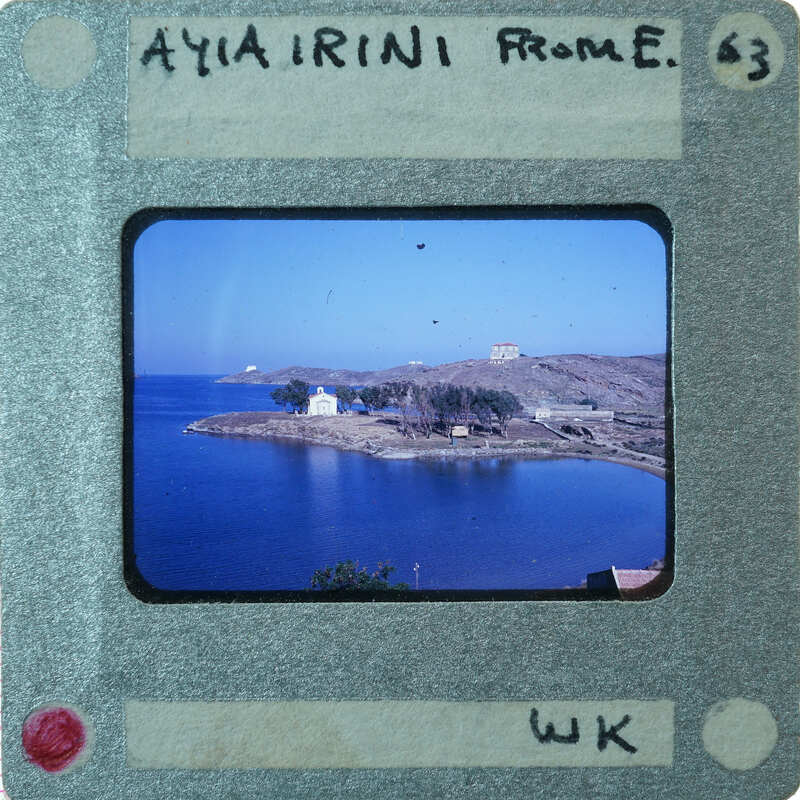 Old photograph of a coastal village with a body of water and buildings.