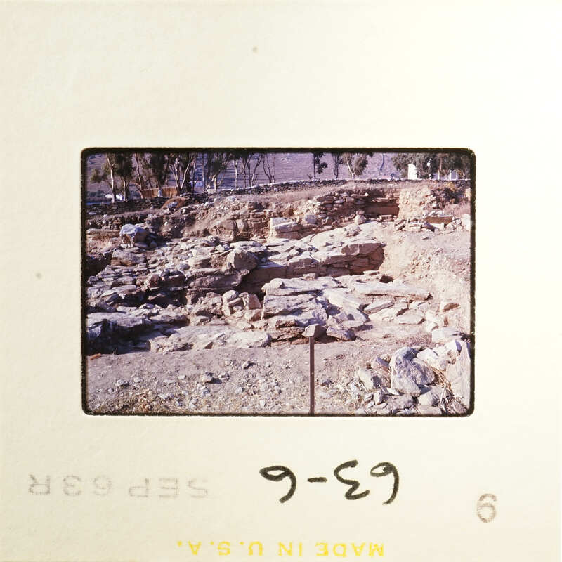 Ancient ruins with stone structures and vegetation, captured on an old photograph.