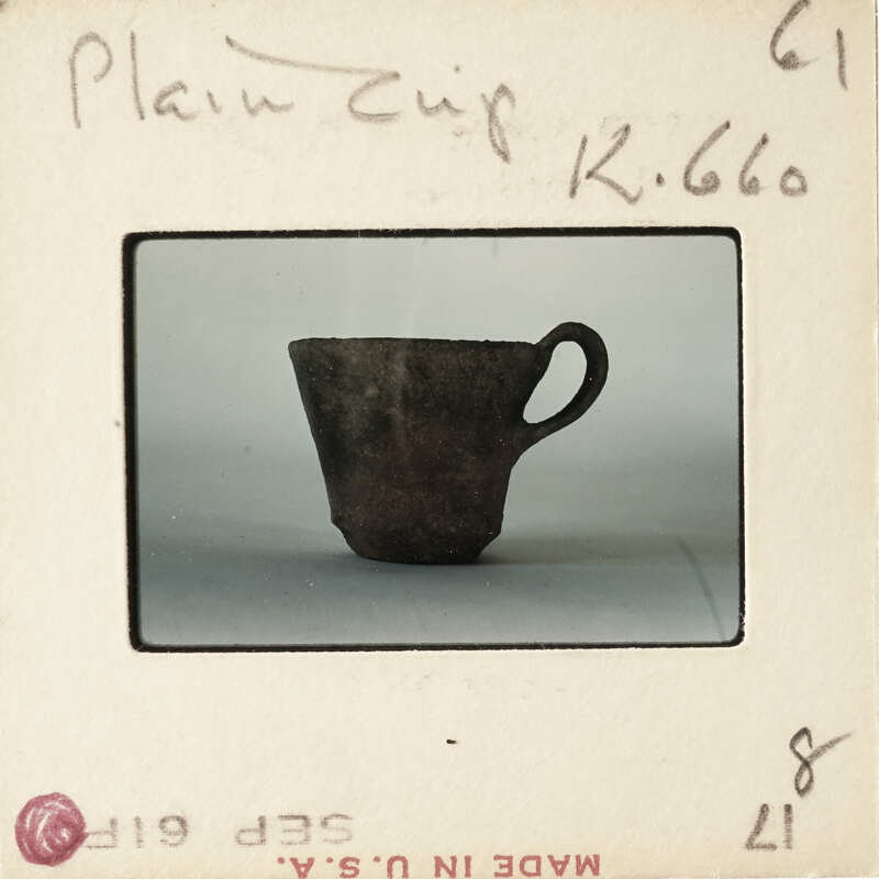 Small clay cup on white surface with vintage photo label.