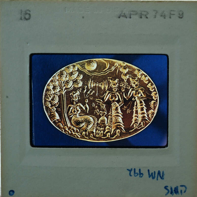 Gold ring with intricate designs and characters on a blue background.