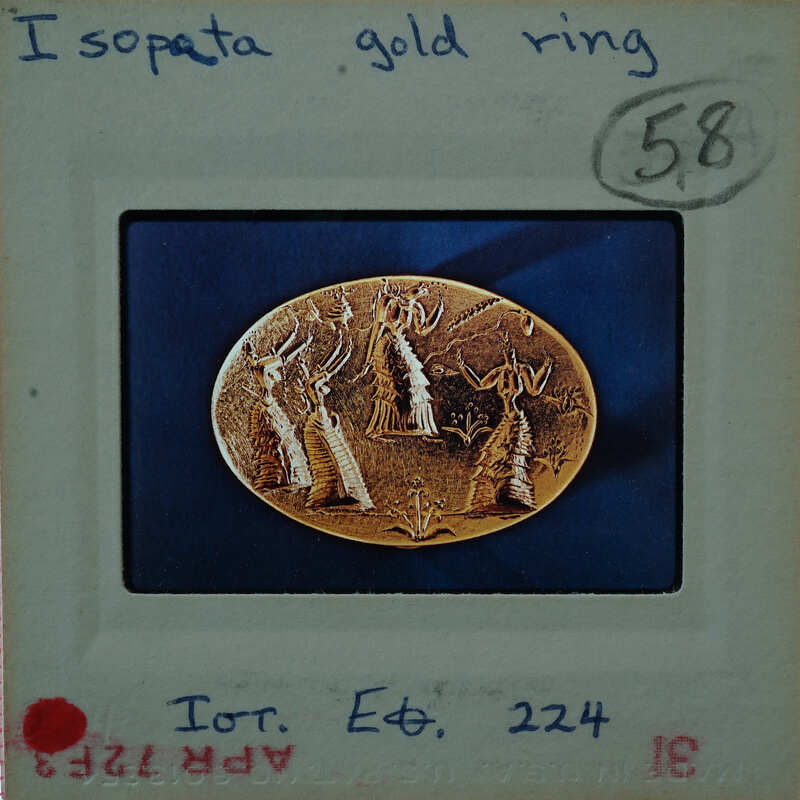 Gold ring with intricate design, possibly depicting a scene or figures, set against a blue background.