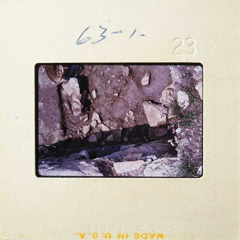 A photograph showing a rocky terrain with patches of grass and dirt.