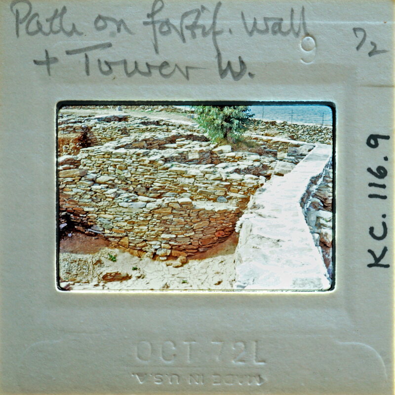 A vintage photograph of a stone wall and tower with handwritten notes on the back.