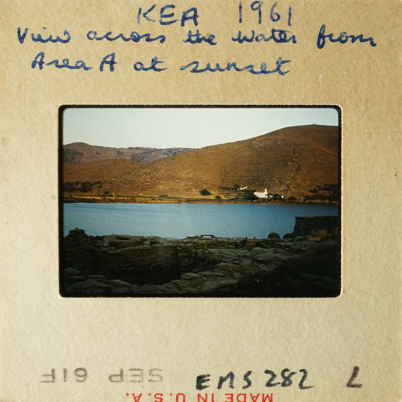 A photograph showing a tranquil lake scene at sunset with mountains in the background.