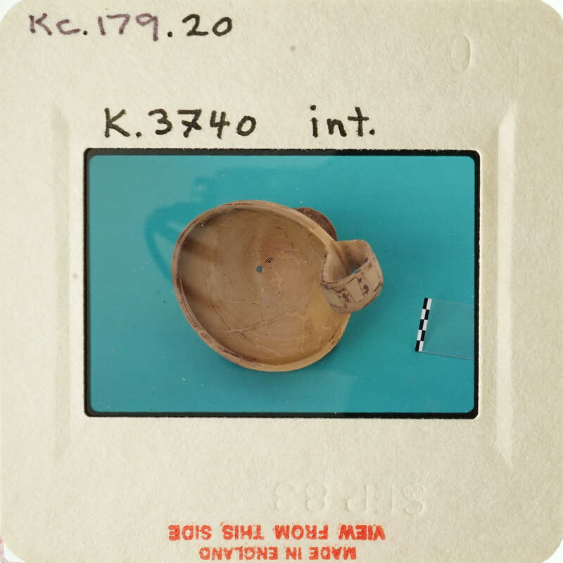 A photograph of an ancient pottery shard with visible markings and texture, set against a blue background.