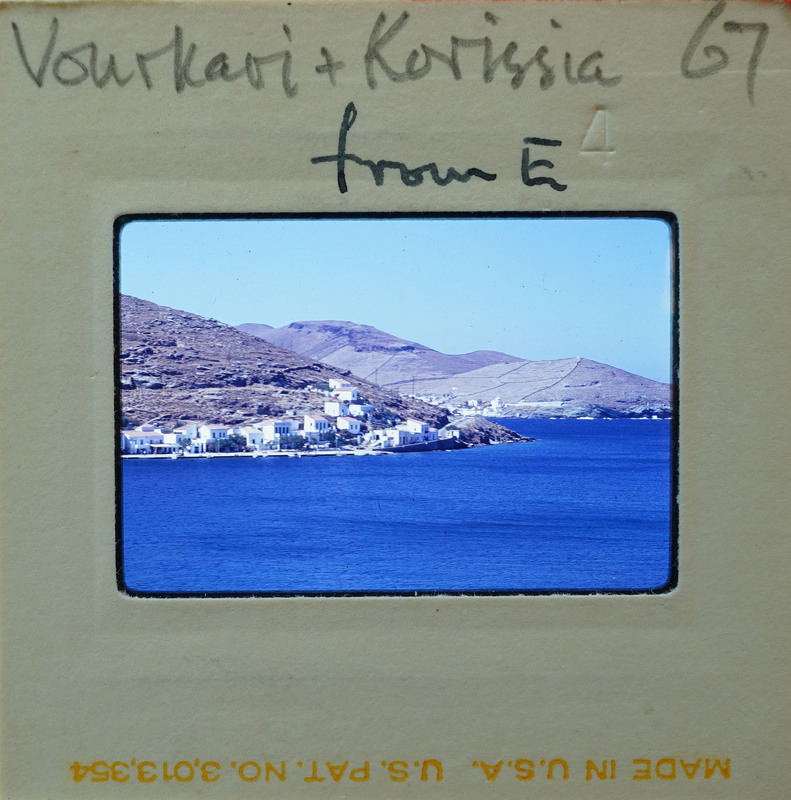 A coastal village with blue water and mountains.