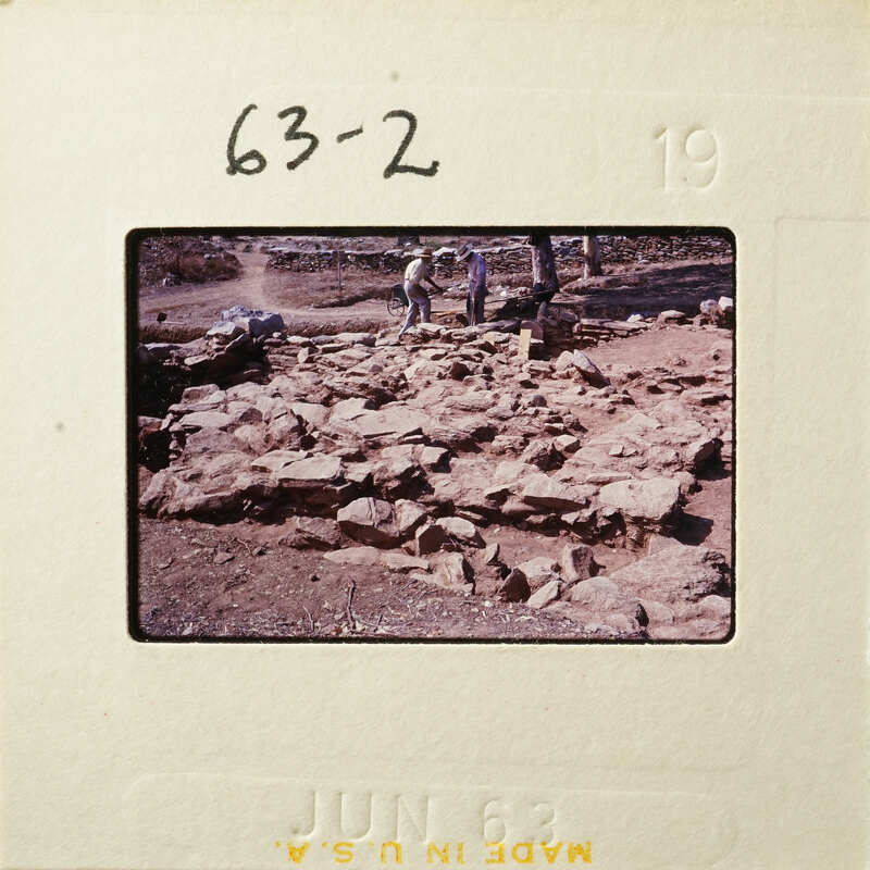 A group of people working on an archaeological site with stone ruins.