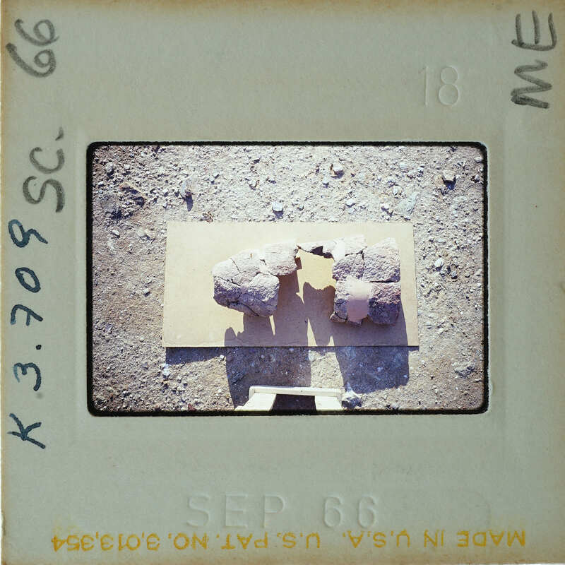 A photograph of two rocks on a surface with a shadow cast by the photographer's hand.