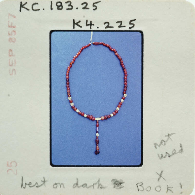 Red bead necklace with a tassel on a blue background.