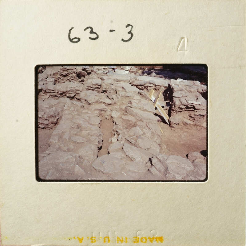 A person standing near an ancient archaeological site with stone ruins.