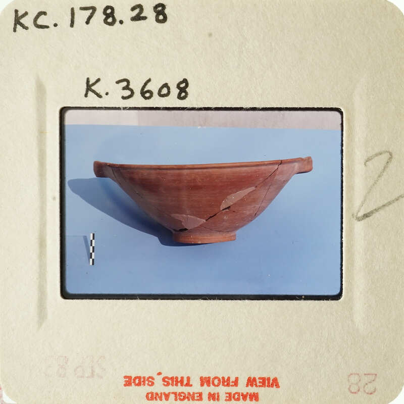 A photograph of an ancient ceramic bowl with visible cracks and imperfections, displayed on a blue surface.