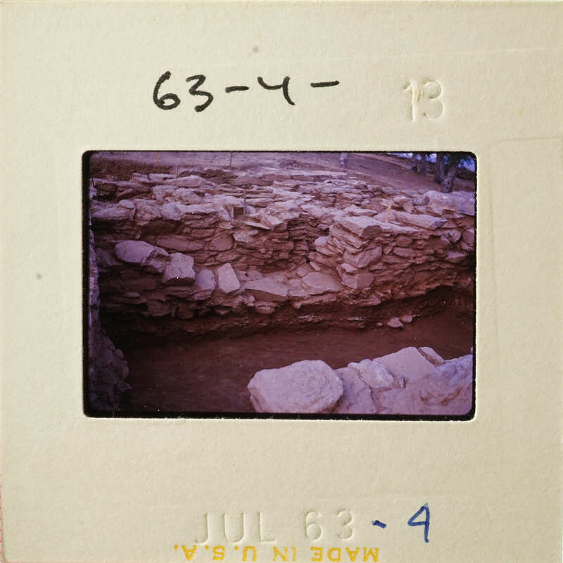 Ancient ruins with stone walls and dirt ground, photographed on a film strip.