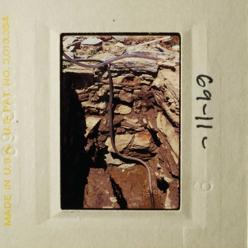 This is an image of an old slide showing a rock wall with exposed pipes and wiring.