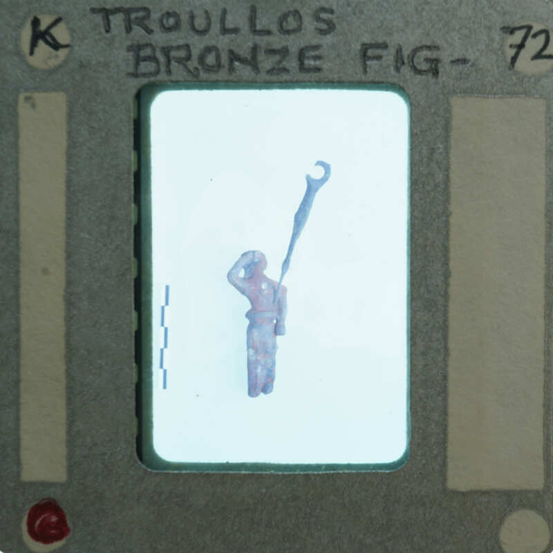 A small figurine of a person with a staff, encased in a plastic holder labeled "Bronze Figurine".