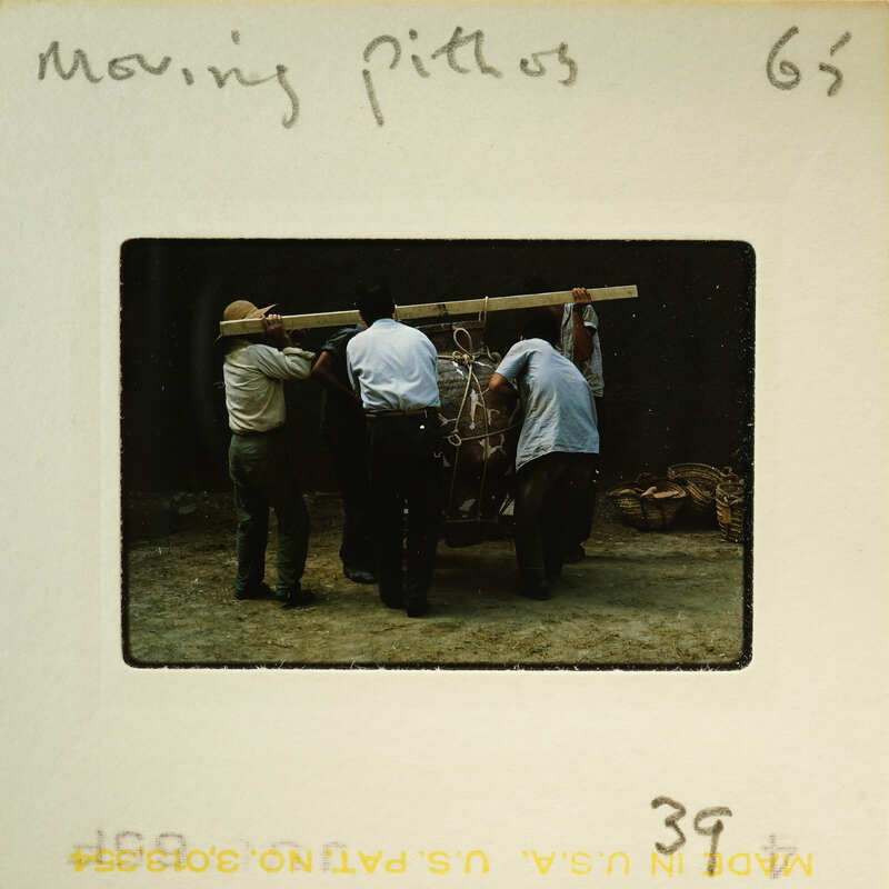 Four men working together to move a large object on a wooden platform.