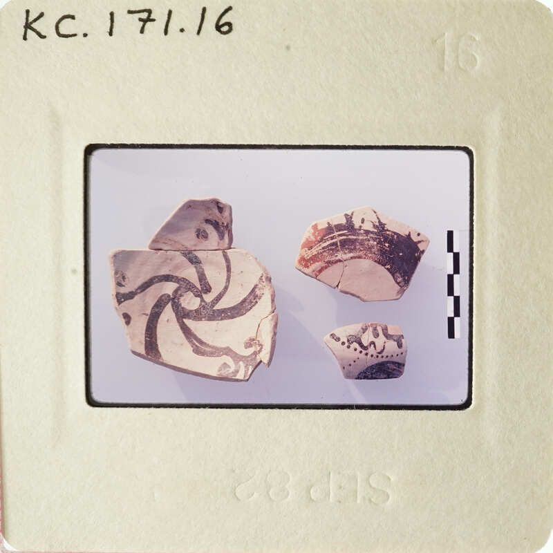 Old ceramic shards with intricate designs on a white surface.