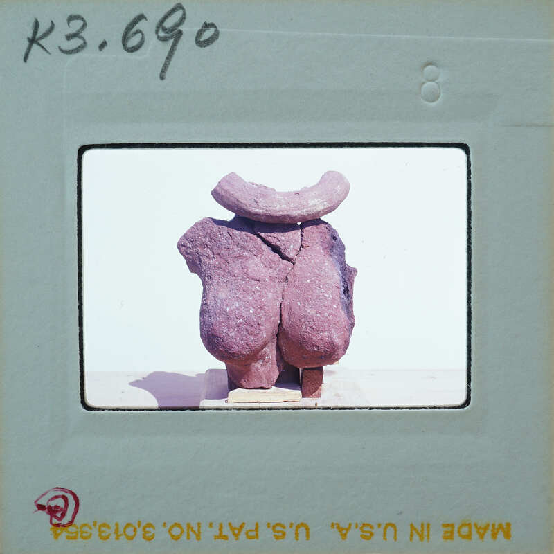 A photograph of a sculpture made from rocks, displayed on a stand with a white background.