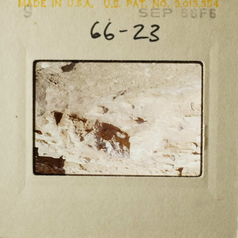 A faded photograph of a rocky surface with a small, dark object on it.