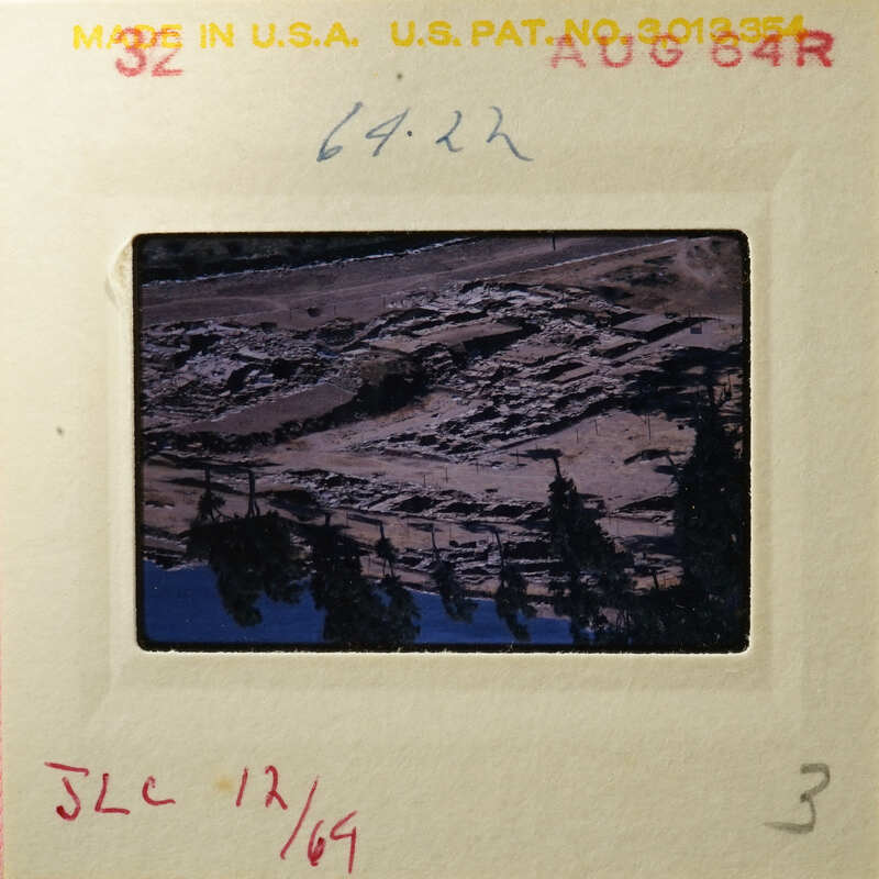 Aerial view of rugged terrain with trees, captured on an old photographic slide.