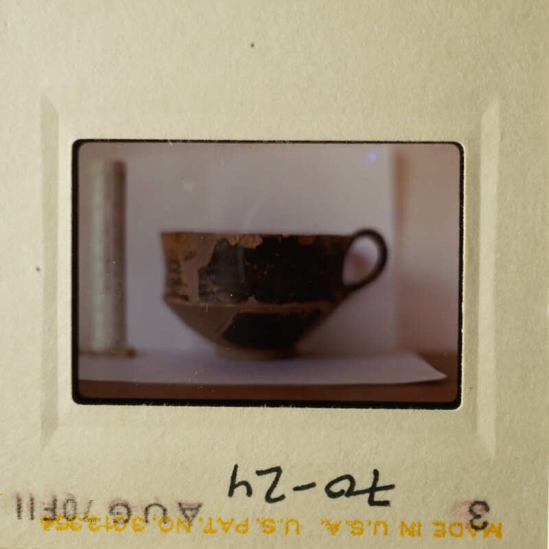 The photo shows an old-fashioned coffee cup on a table, with a white background and a focus on the cup.