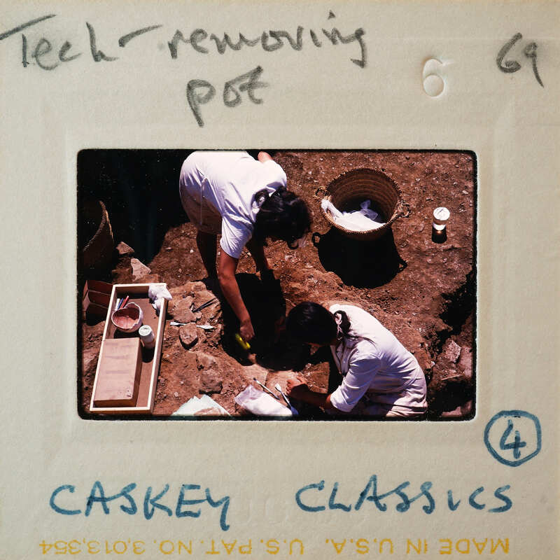 A photograph of two people working on a project with various items around them, including what appears to be a piece of pottery.