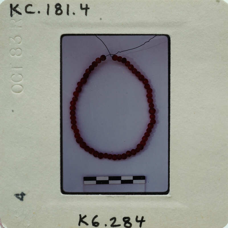 A bracelet with red beads on a white background.