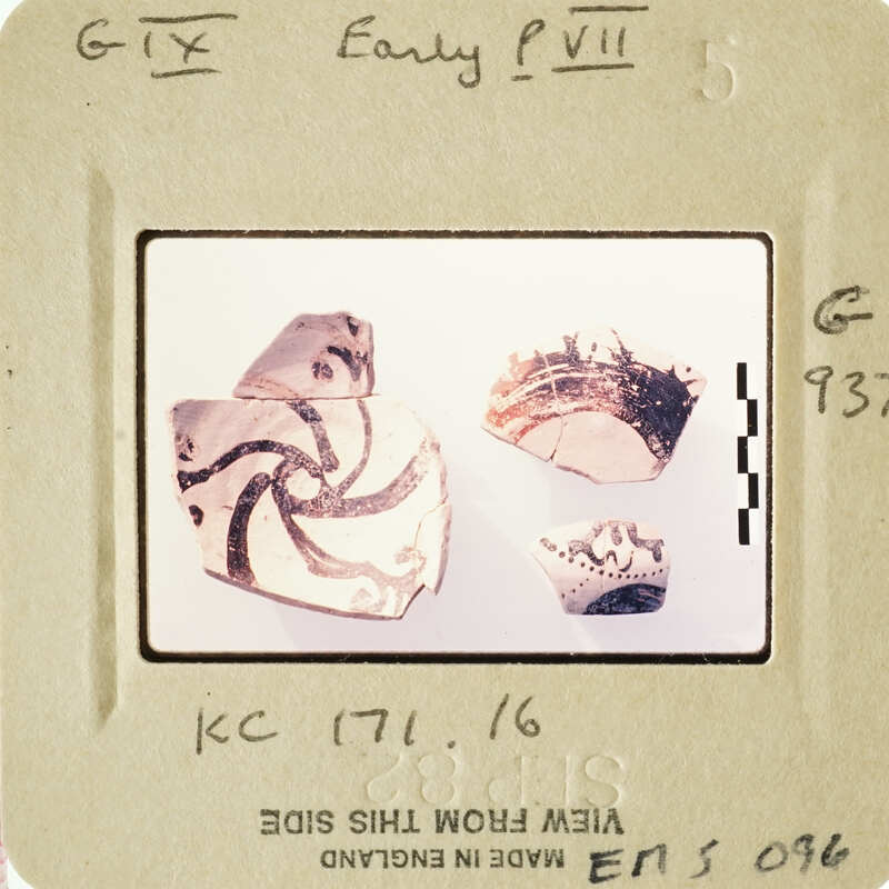 Photograph of ancient pottery shards with intricate designs on a white surface.