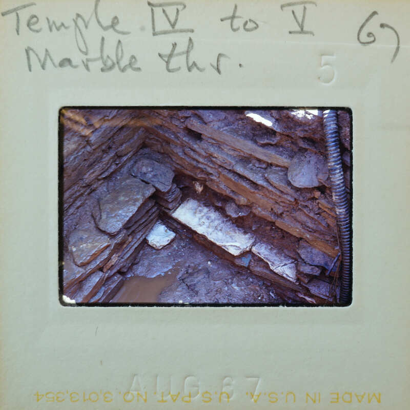 Stone walls forming a corner highlighting a piece of marble used in its construction.