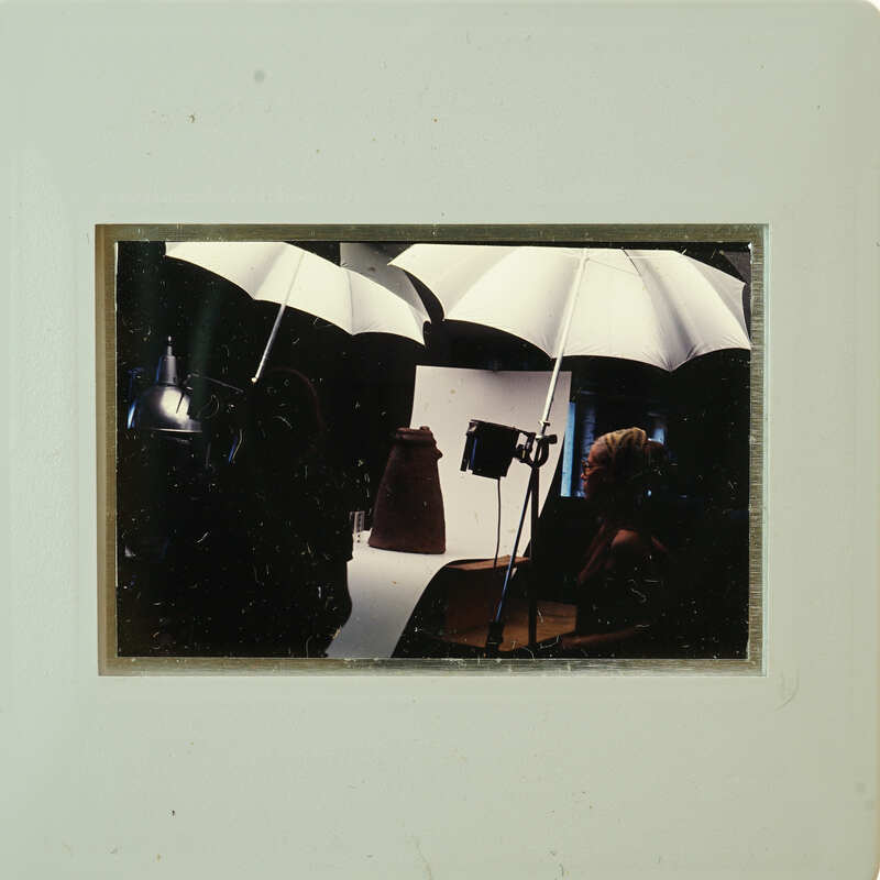 Photographer with umbrellas and lights, taking a portrait of a person.