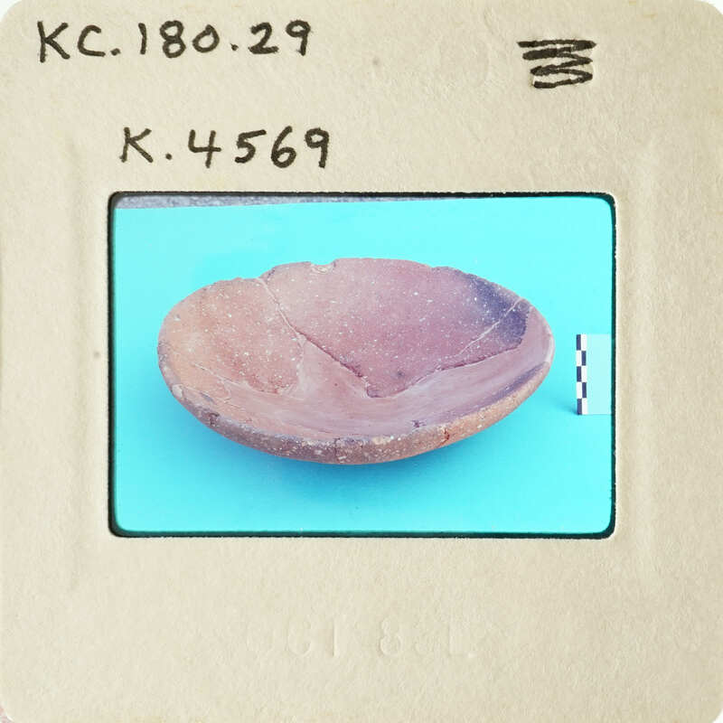 Old ceramic bowl with cracks and chips on blue surface.