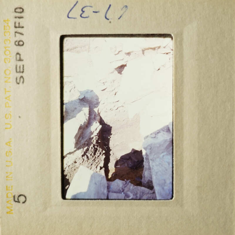 The image shows a rocky landscape with a dark crevice, taken from an elevated angle.