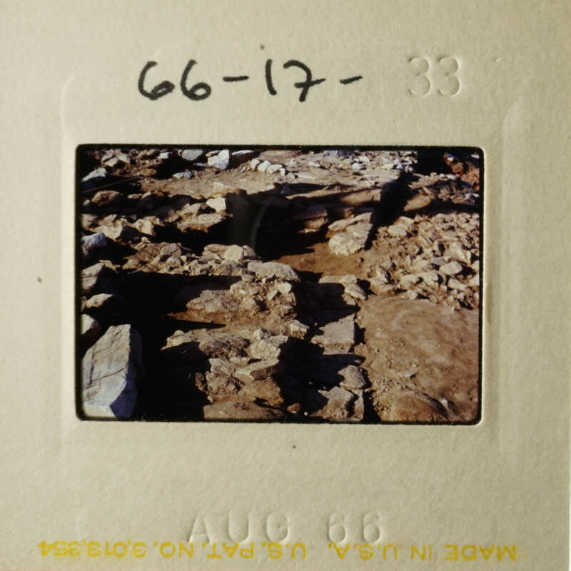 This is an image of a rocky landscape with a focus on a pile of rocks and a person standing behind them.