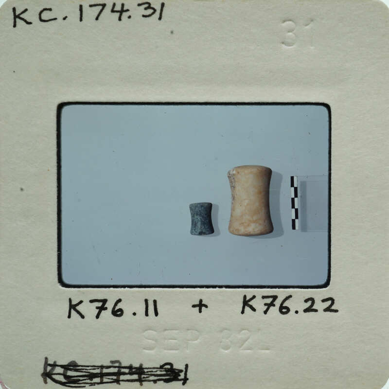 Two small objects, possibly beads or jewelry, on a white surface.