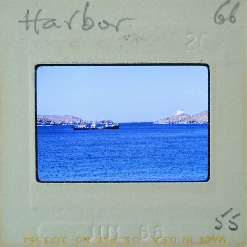 A vintage photo of a harbor with boats and calm waters, framed by an old film strip.