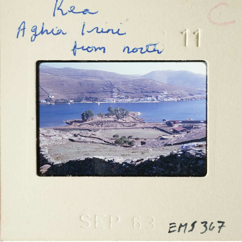 A sepia-toned photograph depicting an island landscape with a body of water and ruins, signed "Keo Aghi Rini" from North.