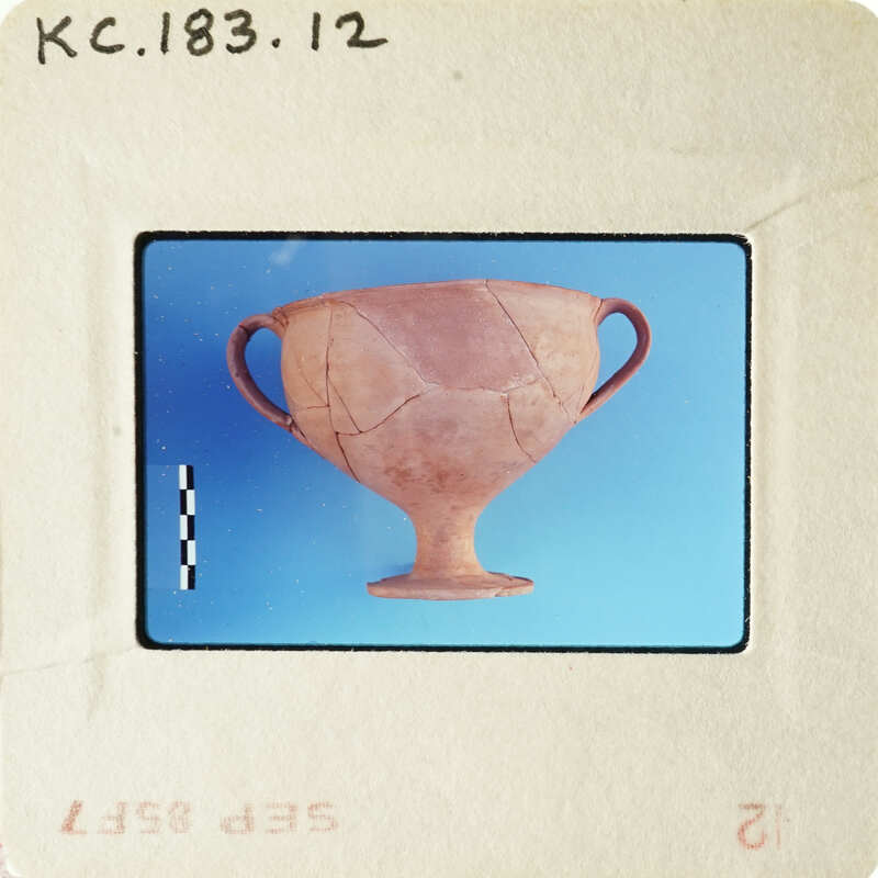 Ancient Greek vase on display with visible cracks and damage.