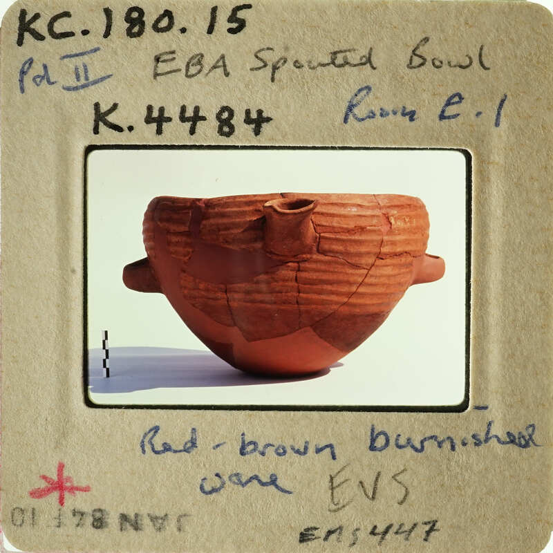 Ancient Greek pottery with red-figure technique, displayed on a white stand.