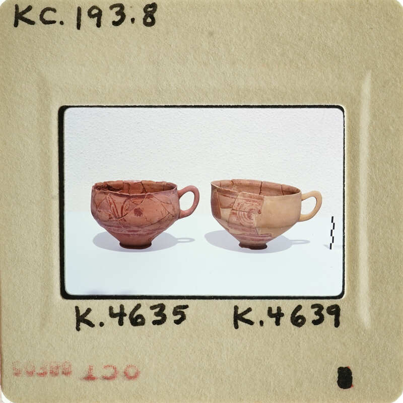 Two ancient Greek vases with red and black designs on display.