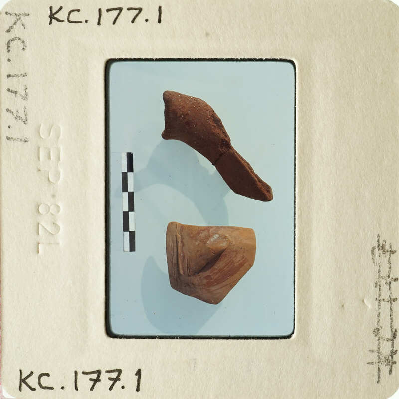 Two ancient clay objects on display, possibly artifacts with labels and measurements.
