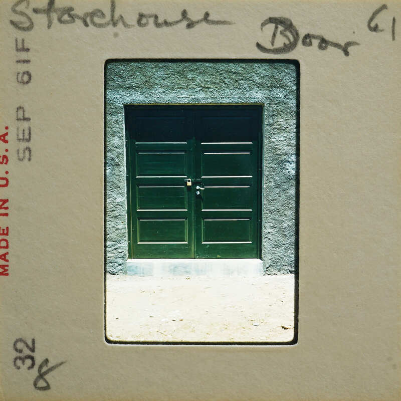 A photograph of a green door with a peeling label on it, displayed within a vintage film strip frame.