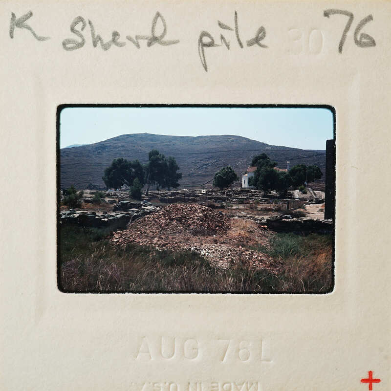 A photograph of a rocky landscape with mountains and sparse vegetation, dated August 1976.