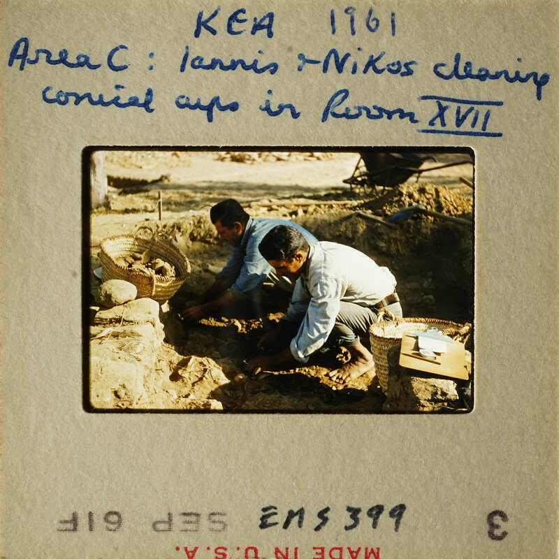 Two men working on cleaning and restoring ancient artifacts, possibly pottery, at an archaeological site.