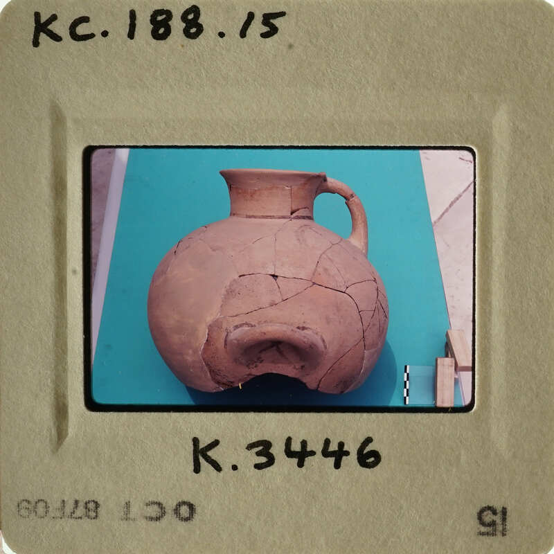 Ancient ceramic vase with visible cracks and chips, displayed on a table.