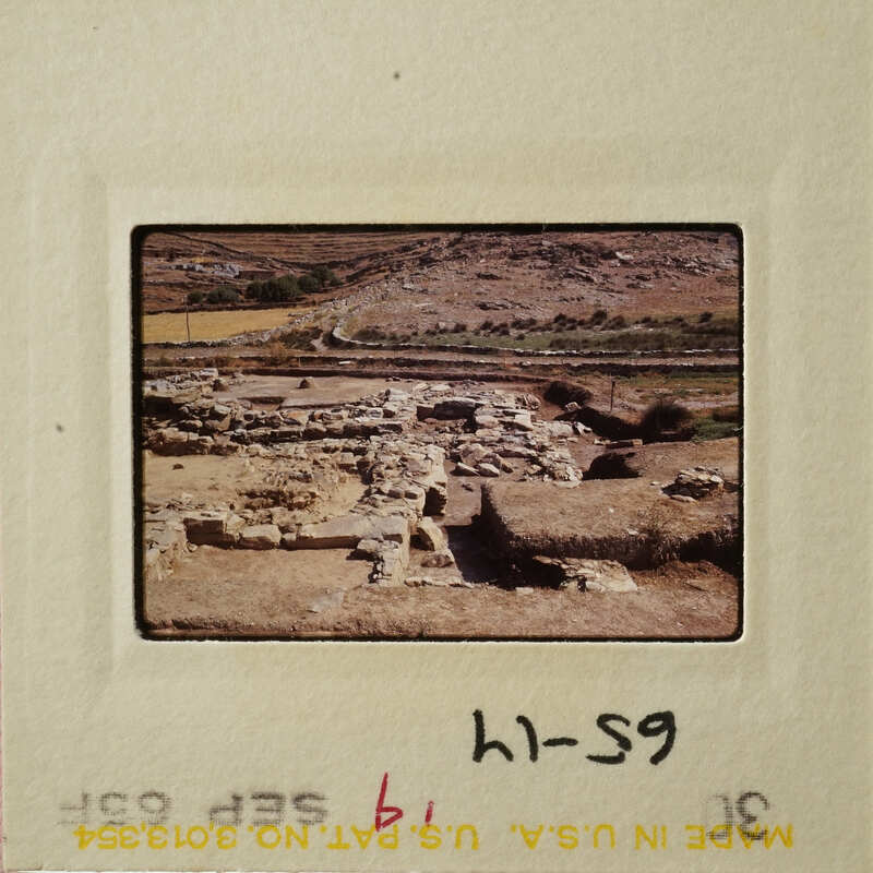 Ancient ruins with stone walls and pathways, set against a backdrop of arid landscape.