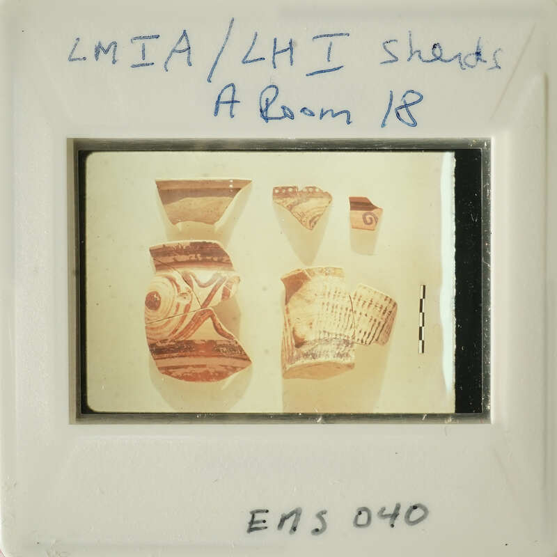 Ancient pottery displayed on a white surface, with some pieces broken and arranged next to each other.