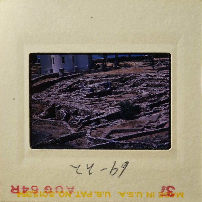 Ancient ruins with stone walls and vegetation, taken from an elevated perspective.